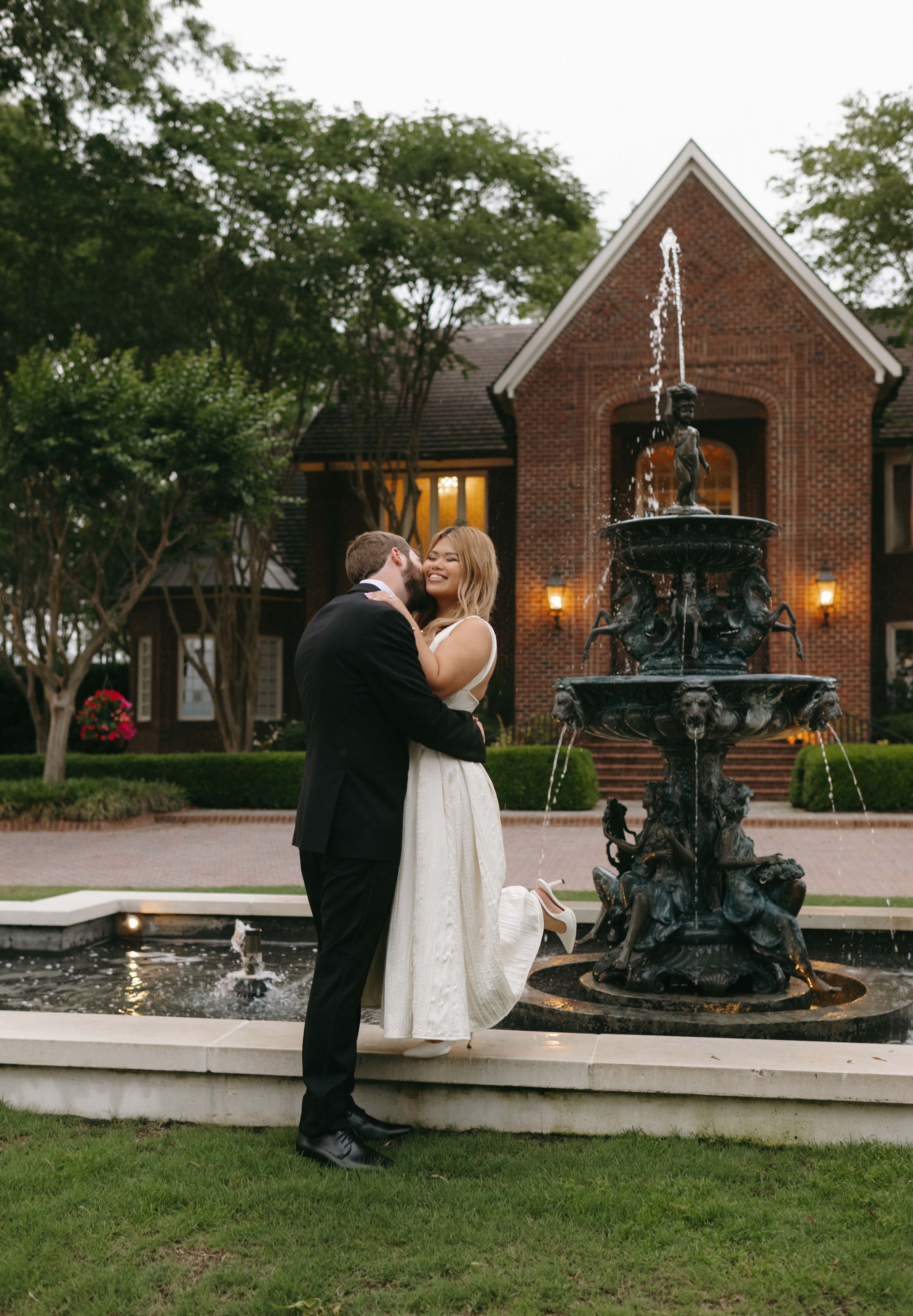 Romantic evening photos by ornate iron fountain outside brick chapel.