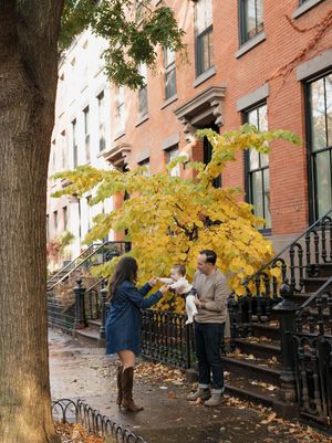 Autumn scene with falling leaves on a historic brick-lined street.