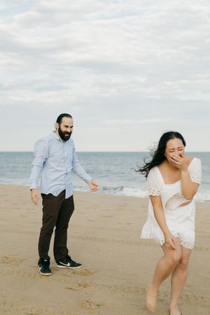 Playful beach scene with couple enjoying a candid moment on sandy shoreline.