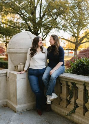 Couple sitting together on a stone balustrade during a golden autumn afternoon.