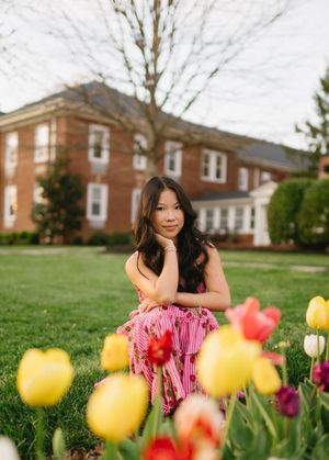Colorful spring tulips frame a garden scene with brick buildings in background.