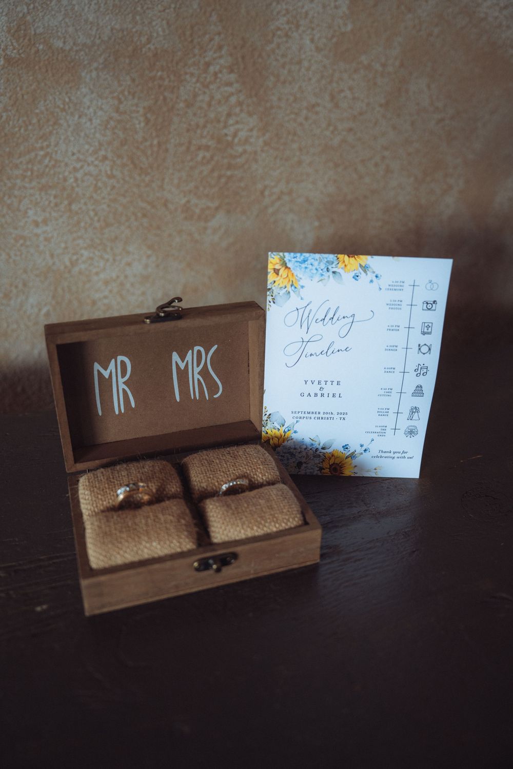 Wedding ring boxes and stationery with sunflower theme displayed on dark surface.