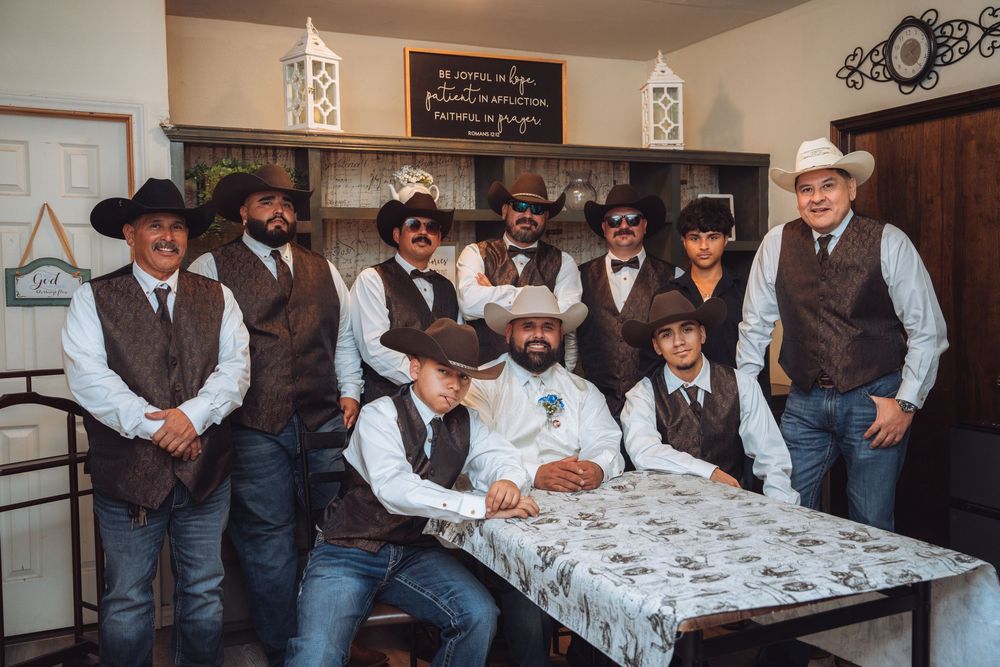 Wedding party in cowboy attire gathered around a table.