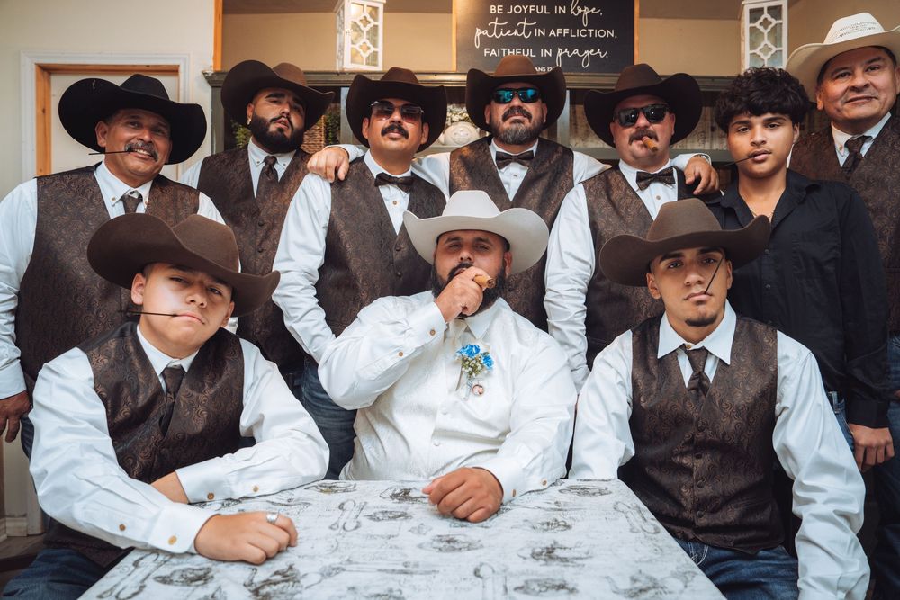 Large group of groomsmen in western wear posing together at wedding.