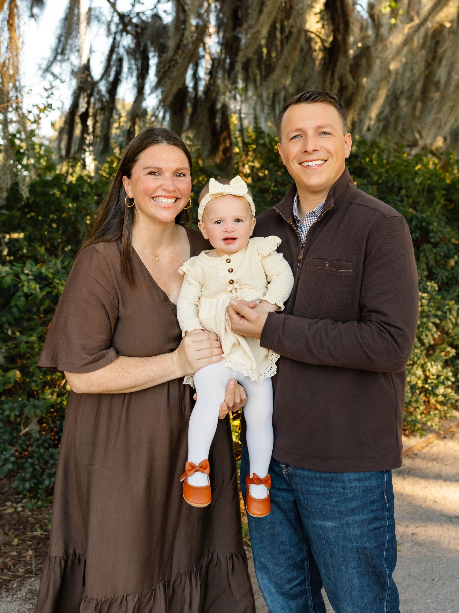 Family portrait session outdoors with Spanish moss trees in background.