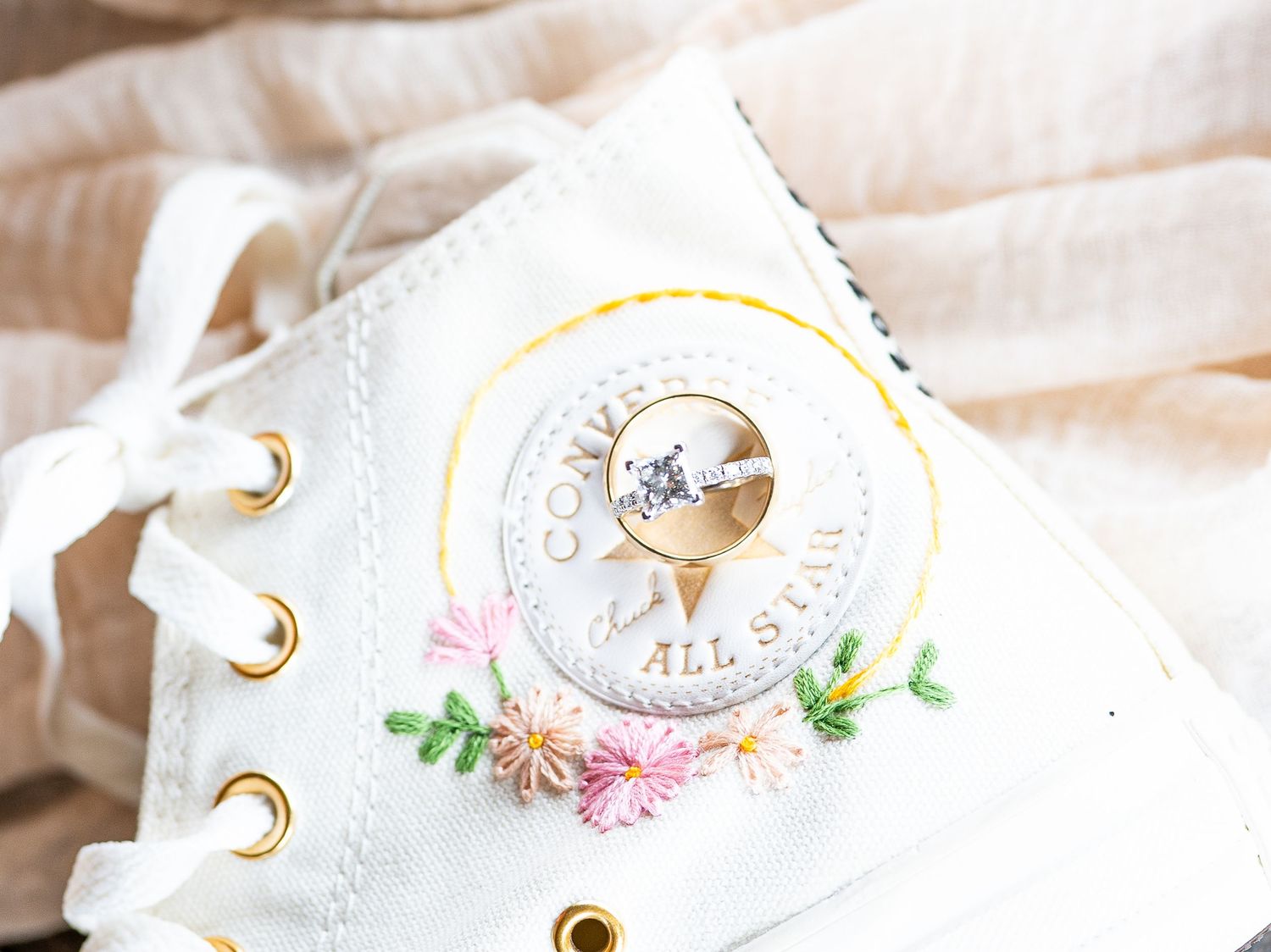 White card stock paper being assembled into a DIY wedding invitation with gold grommets and floral details.