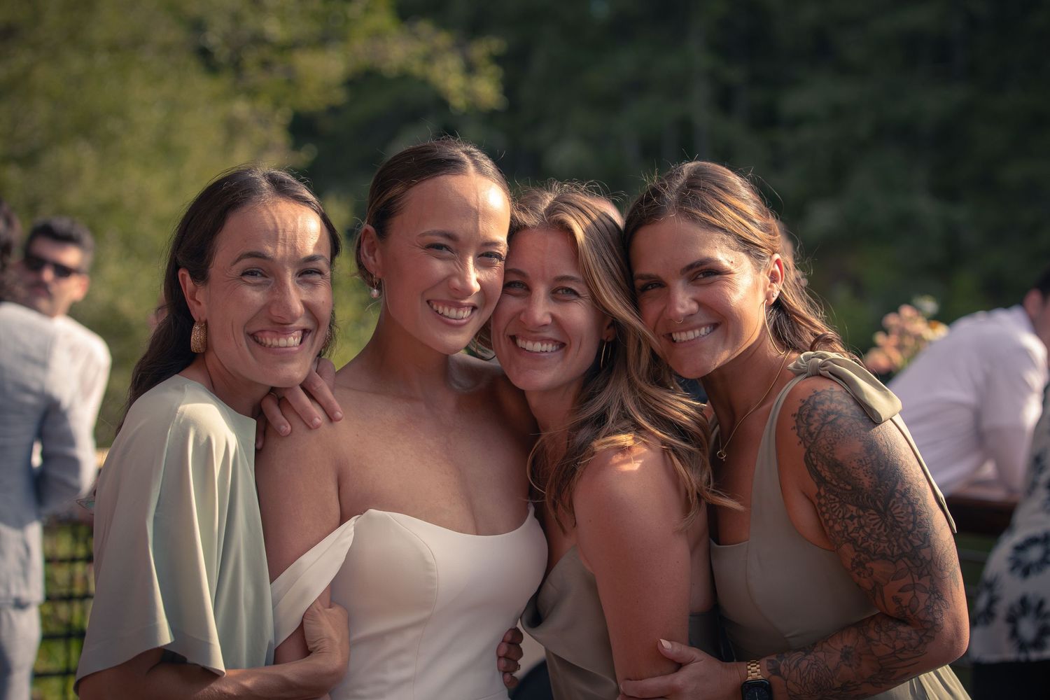 Group of wedding guests smiling and celebrating at an outdoor reception.