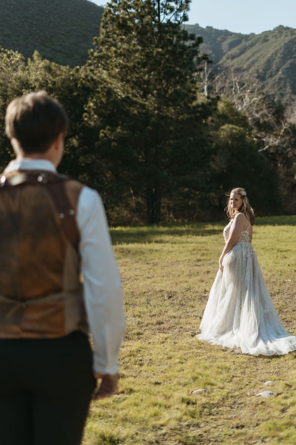 A series of wedding photos showing a bride in a white dress standing in a sunlit meadow with mountains in the background.