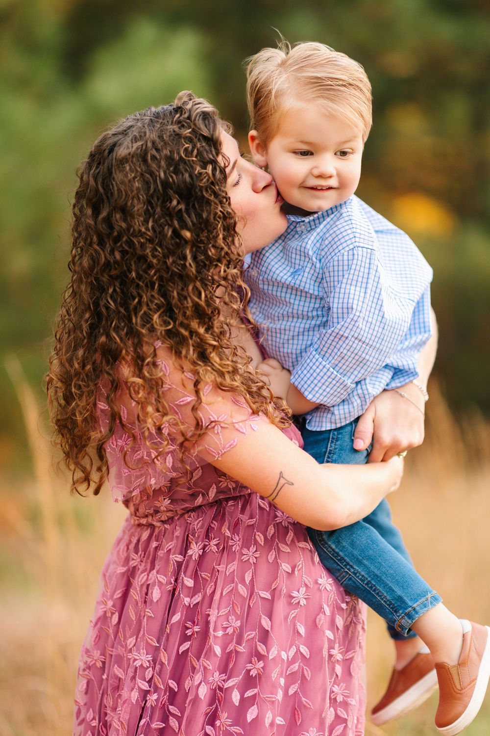 Sweet outdoor portrait sequence showing tender embraces between parent and child wearing blue and pink in a field.