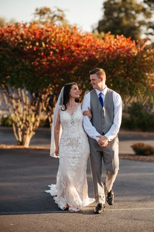A couple shares a romantic moment in front of autumn foliage at sunset during their wedding photoshoot.