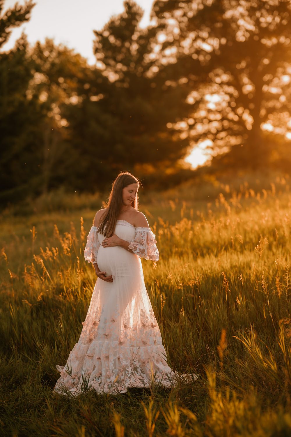 White-dressed figures embrace in a golden sunlit meadow during sunset among tall grasses.