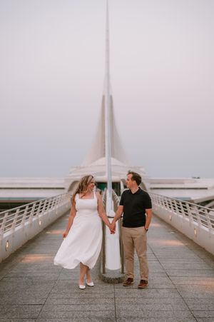 A couple walking along a modern white bridge pier during sunset, capturing progressive romantic poses.