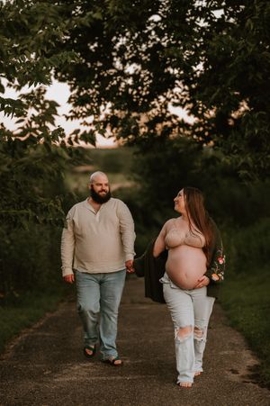 A couple walks together on a sunset path through a lush green park during a romantic evening photoshoot.