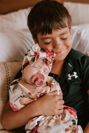 An intimate sequence of a child cuddling with a baby in natural light indoor setting.