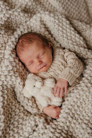 Sleeping newborn wrapped in cozy knitted blanket shown in multiple close-up shots.