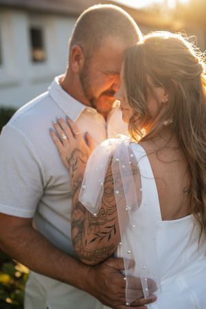A romantic couple shares intimate moments in golden sunlight during an outdoor engagement session.