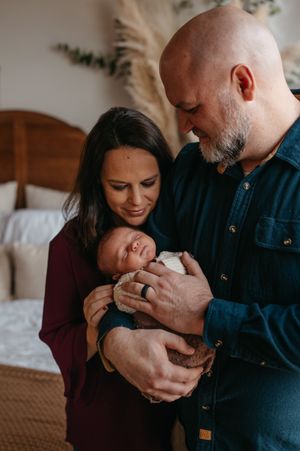 A couple shares tender moments with their newborn baby while sitting together on a couch in a series of intimate photos.