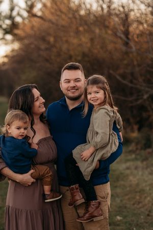 Family embracing outdoors at sunset in autumn with warm earth tones and natural lighting.