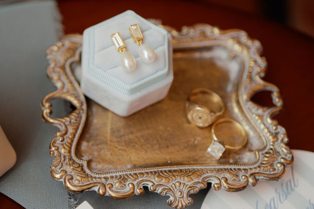 Elegant vintage mirrored vanity tray decorated with jewelry and lit candles in soft, romantic lighting.