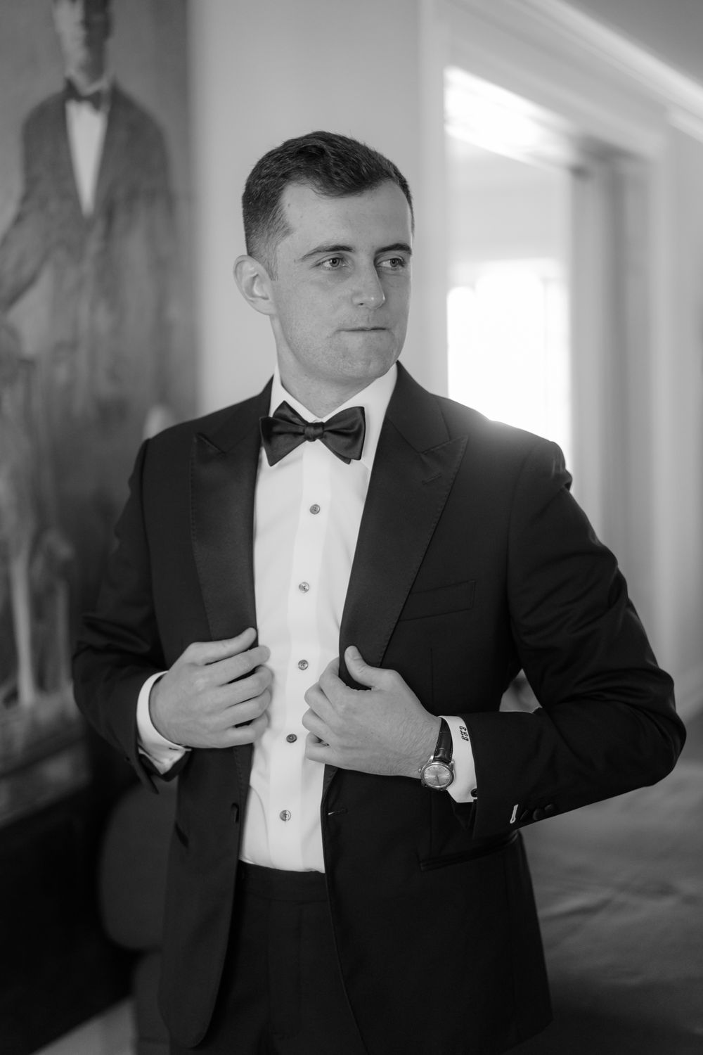 A black and white sequence of photos showing someone adjusting their formal attire and bow tie in a tuxedo.