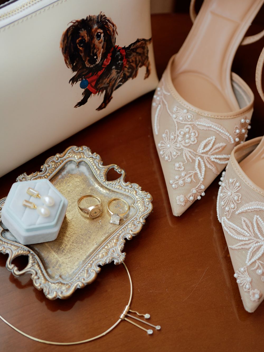 Elegant white embroidered wedding shoes and gold wedding rings displayed on an ornate vintage silver tray.