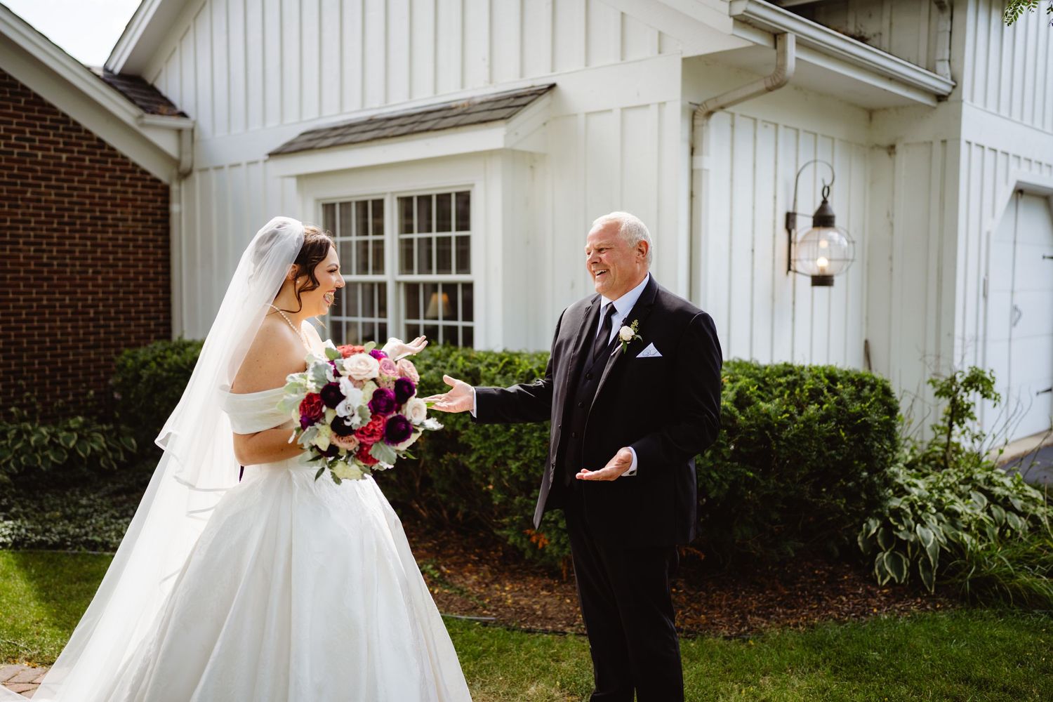 A wedding couple shares intimate first look moments at Olde Mill Inn's elegant outdoor setting in full bridal attire.