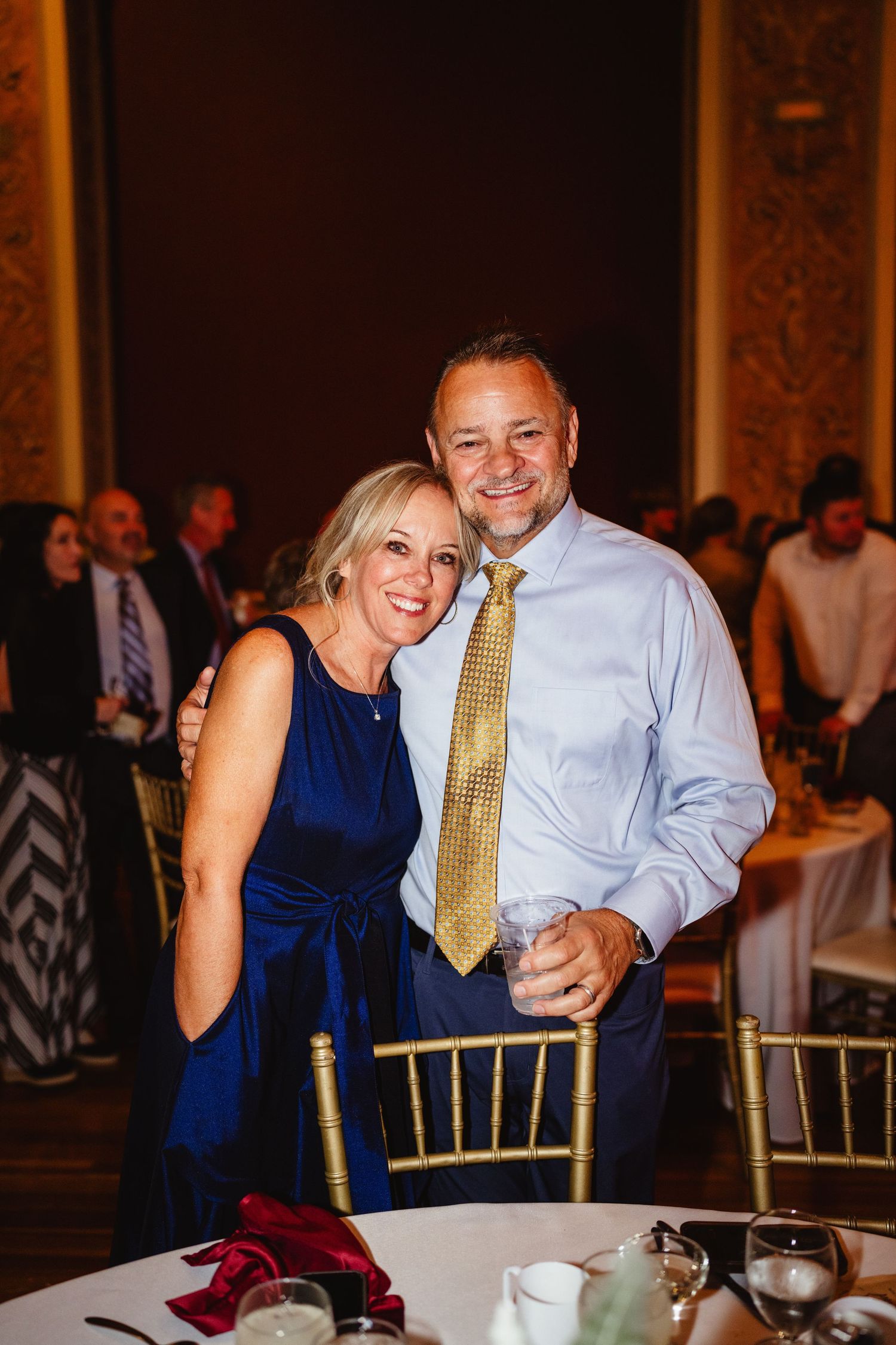 Guests enjoying themselves at an elegant wedding reception with gold chiavari chairs and blue decor.