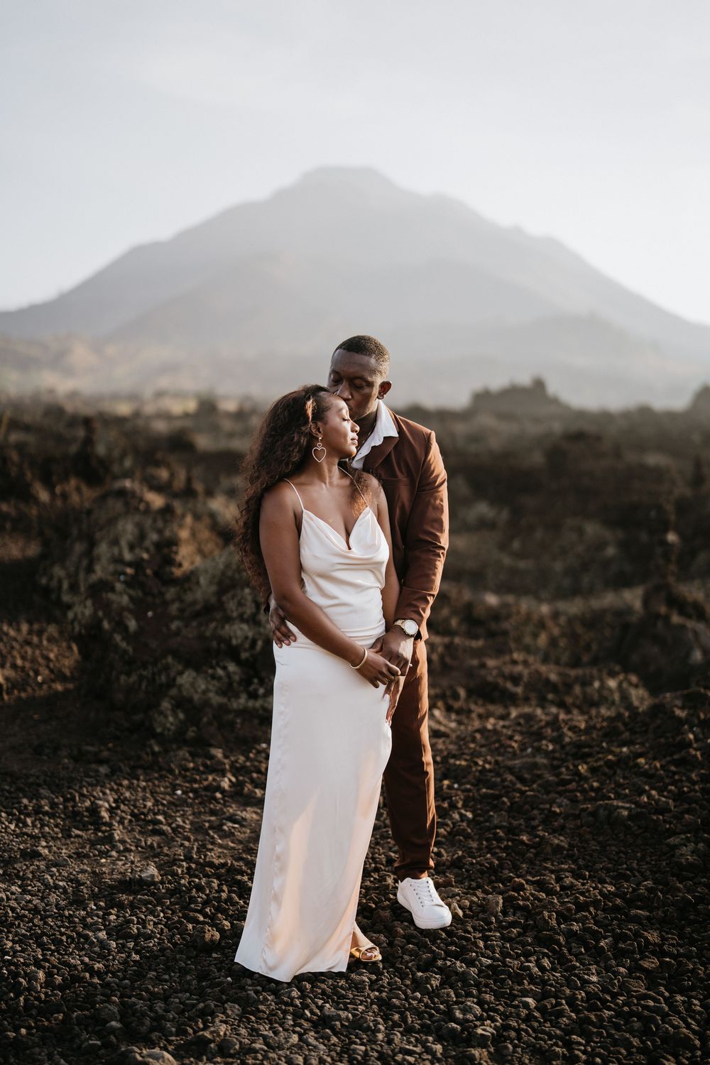 Couple sharing an intimate moment against a mountainous volcanic landscape.