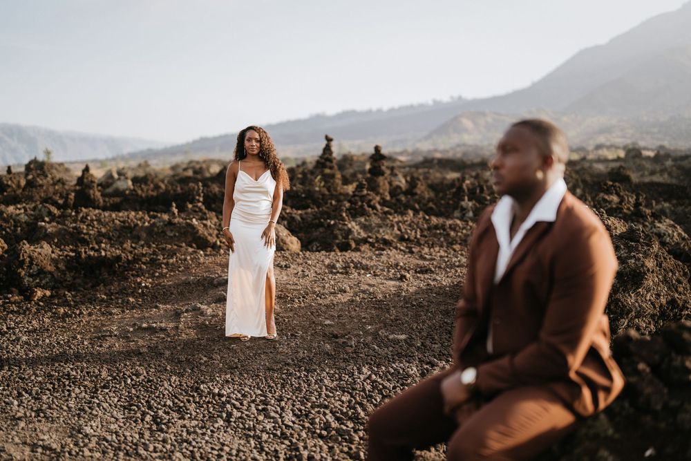 Candid photo session on dark volcanic rocks with mountains in the distance.