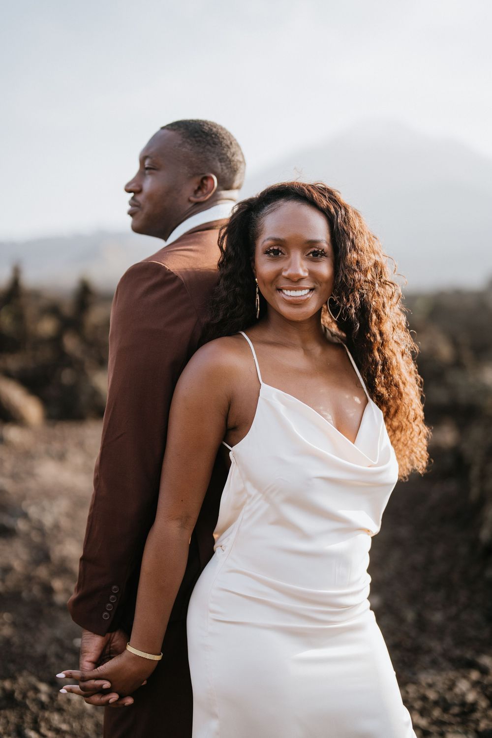 A romantic photoshoot on rocky volcanic terrain with mountains in the distance.