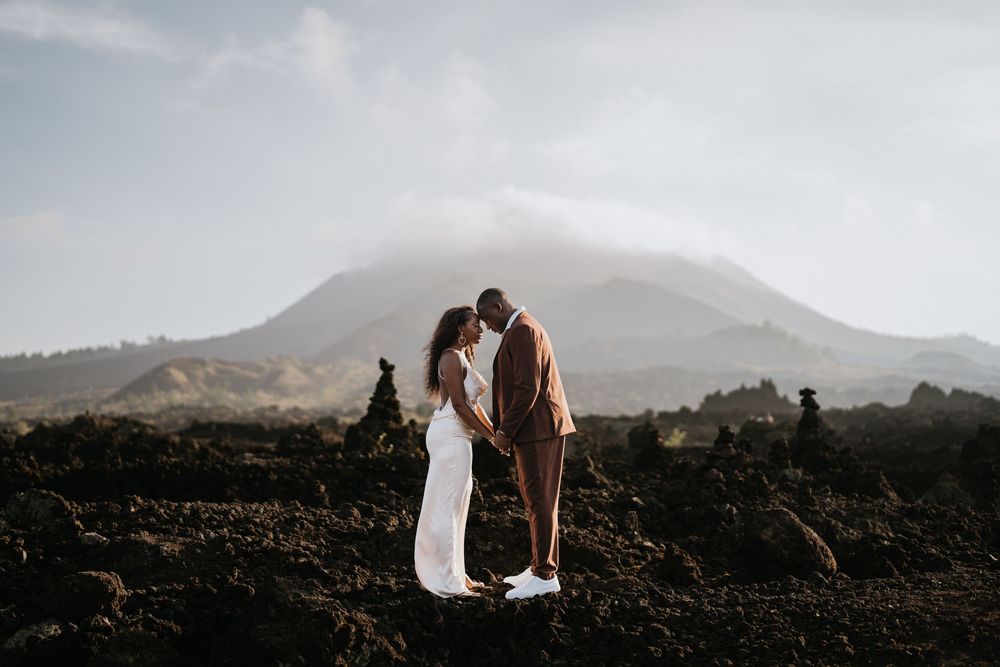 Silhouettes of a couple against a mountainous landscape during golden hour.