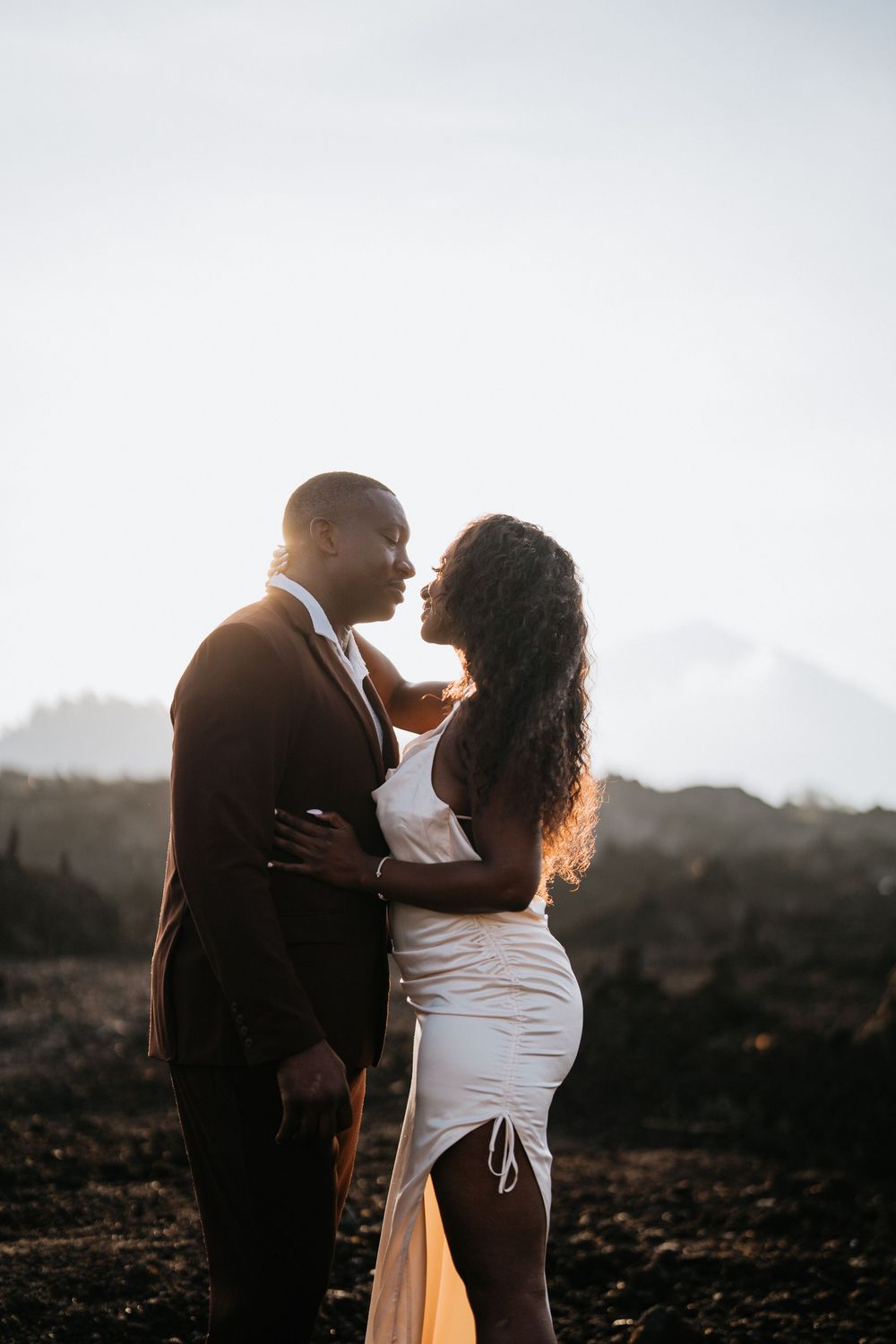 An intimate moment captured between two people on volcanic terrain at sunset.