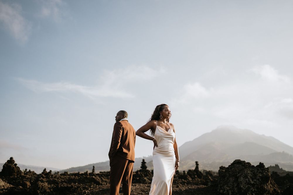 Two figures in flowing white dresses stand against a mountainous backdrop.