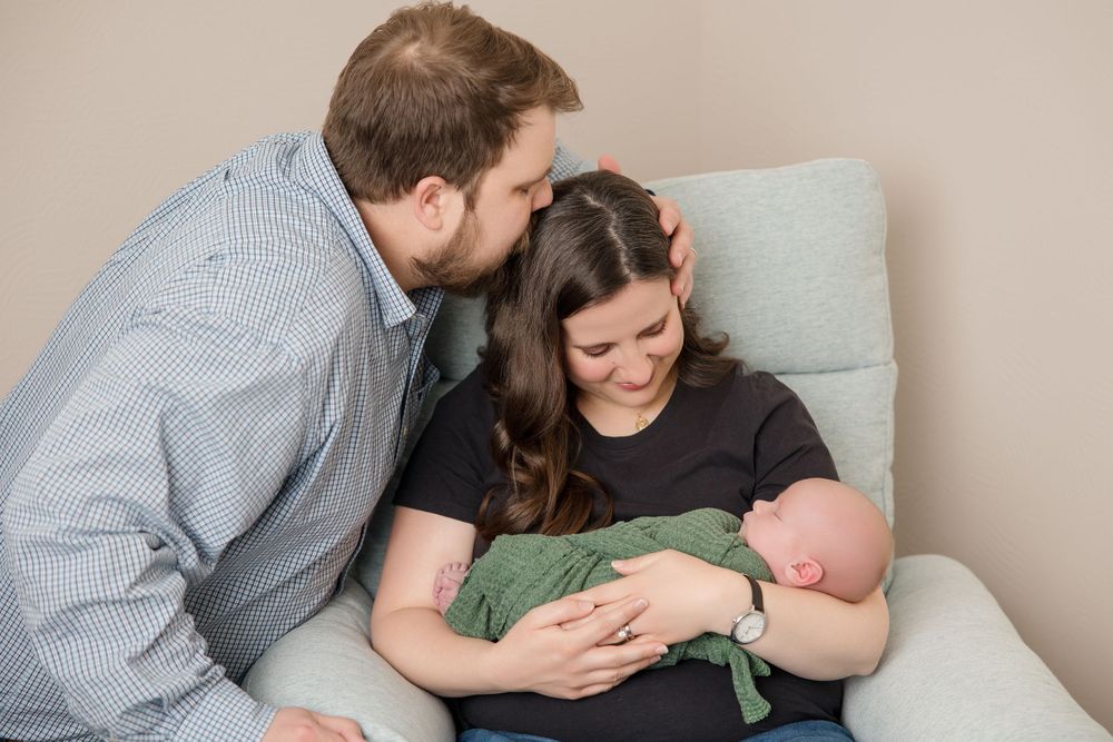 Couple gazing lovingly at their sleeping newborn baby during an intimate photography session.