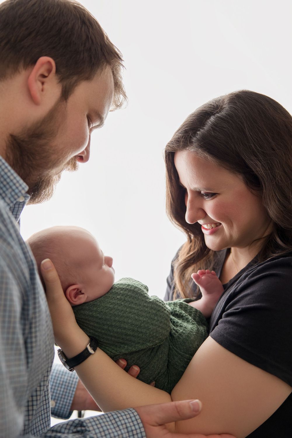 A heartwarming sequence of intimate family moments with parents and their newborn baby wearing green.