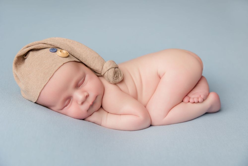 Sleeping baby resting peacefully on soft blue backdrop during professional photoshoot.