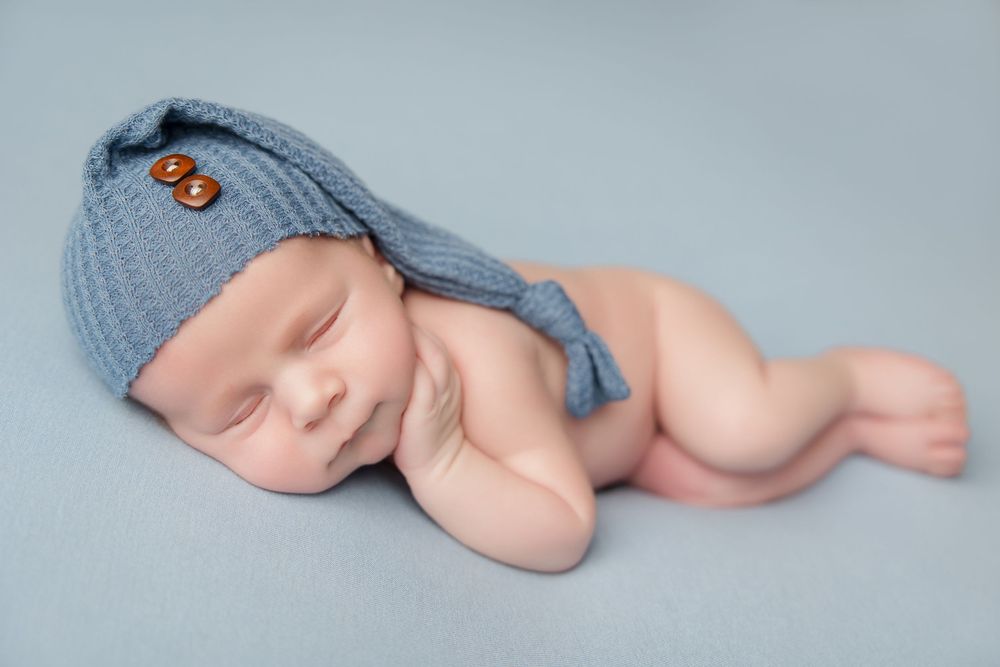 A sleeping newborn baby's bare feet photographed in blue filtered lighting against a plain backdrop, showing progressive angles.
