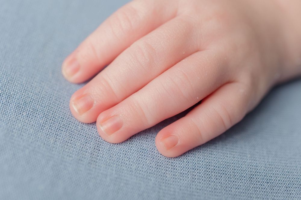 Closeup detail shot of gentle hands resting on textured blue-gray fabric surface.