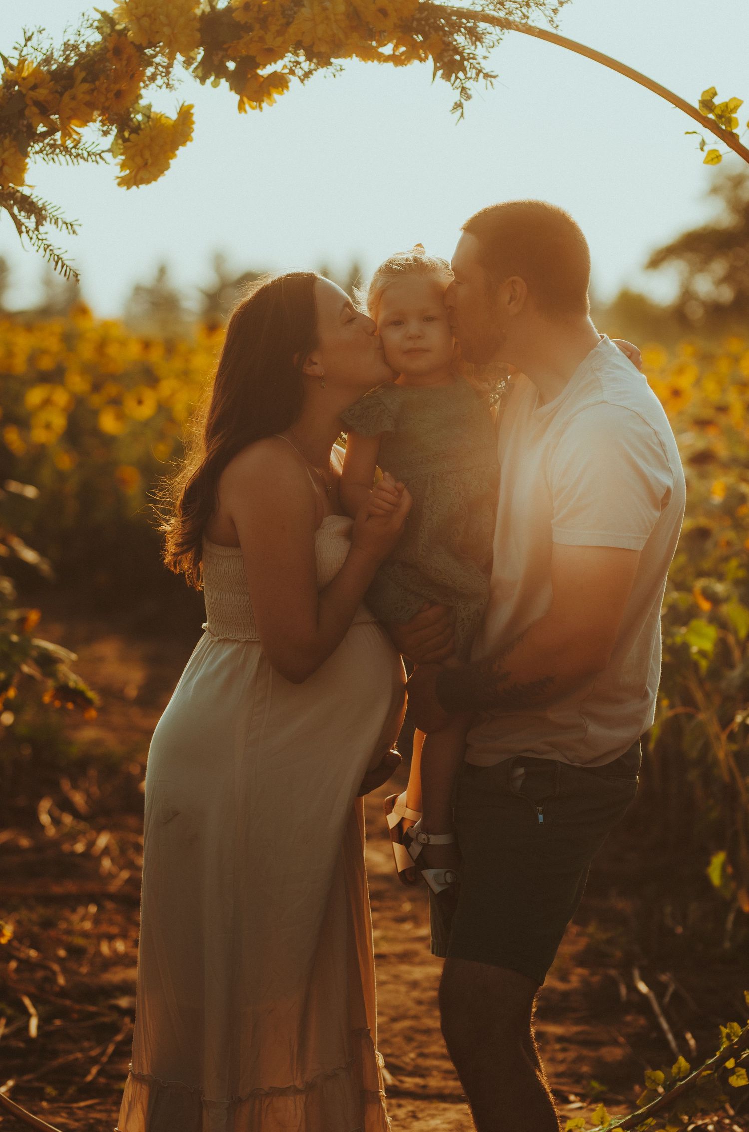 A couple shares tender moments in a sunlit vineyard during golden hour.