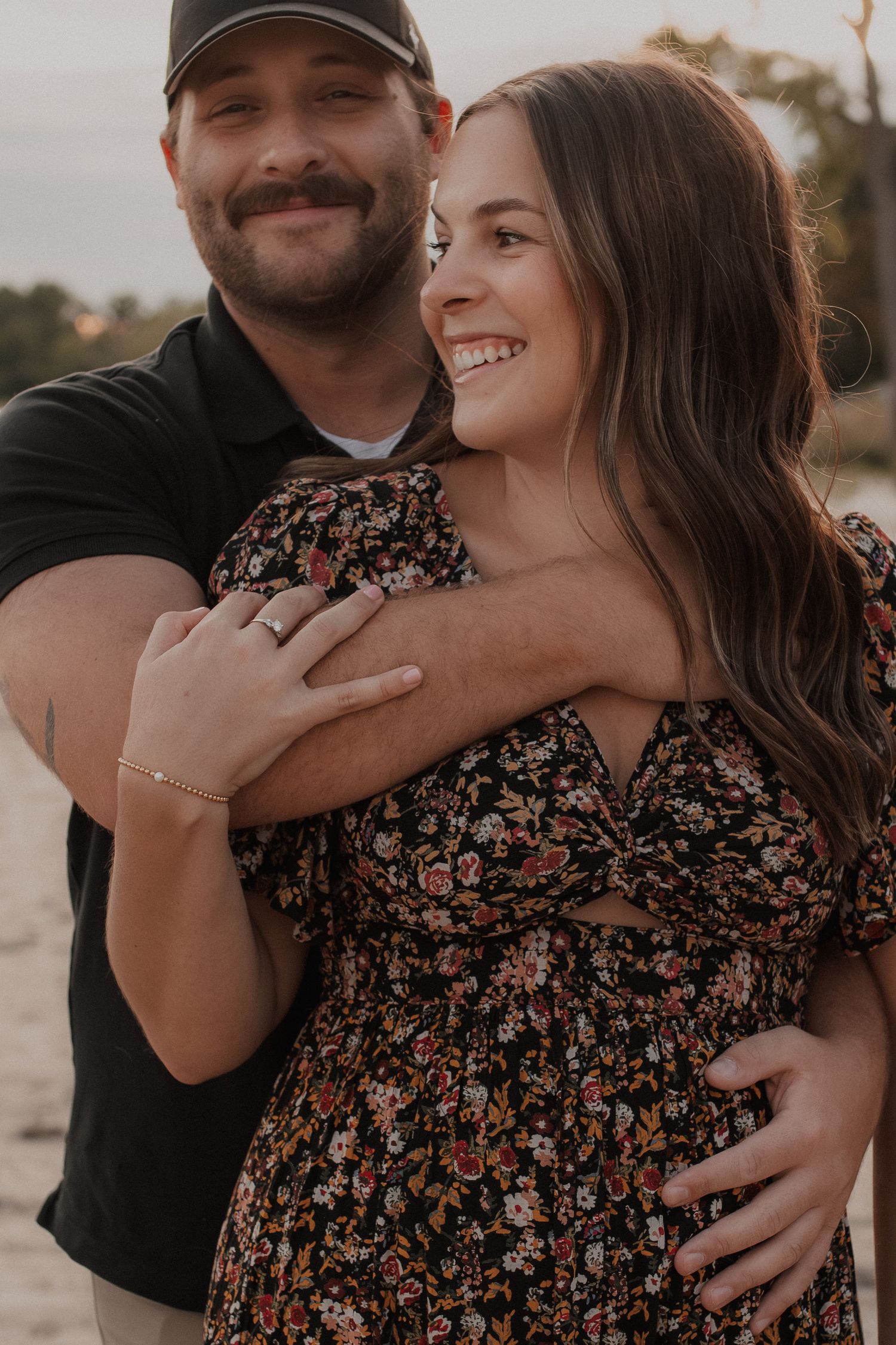 A couple embracing and laughing together at sunset in an outdoor setting with warm autumn lighting.