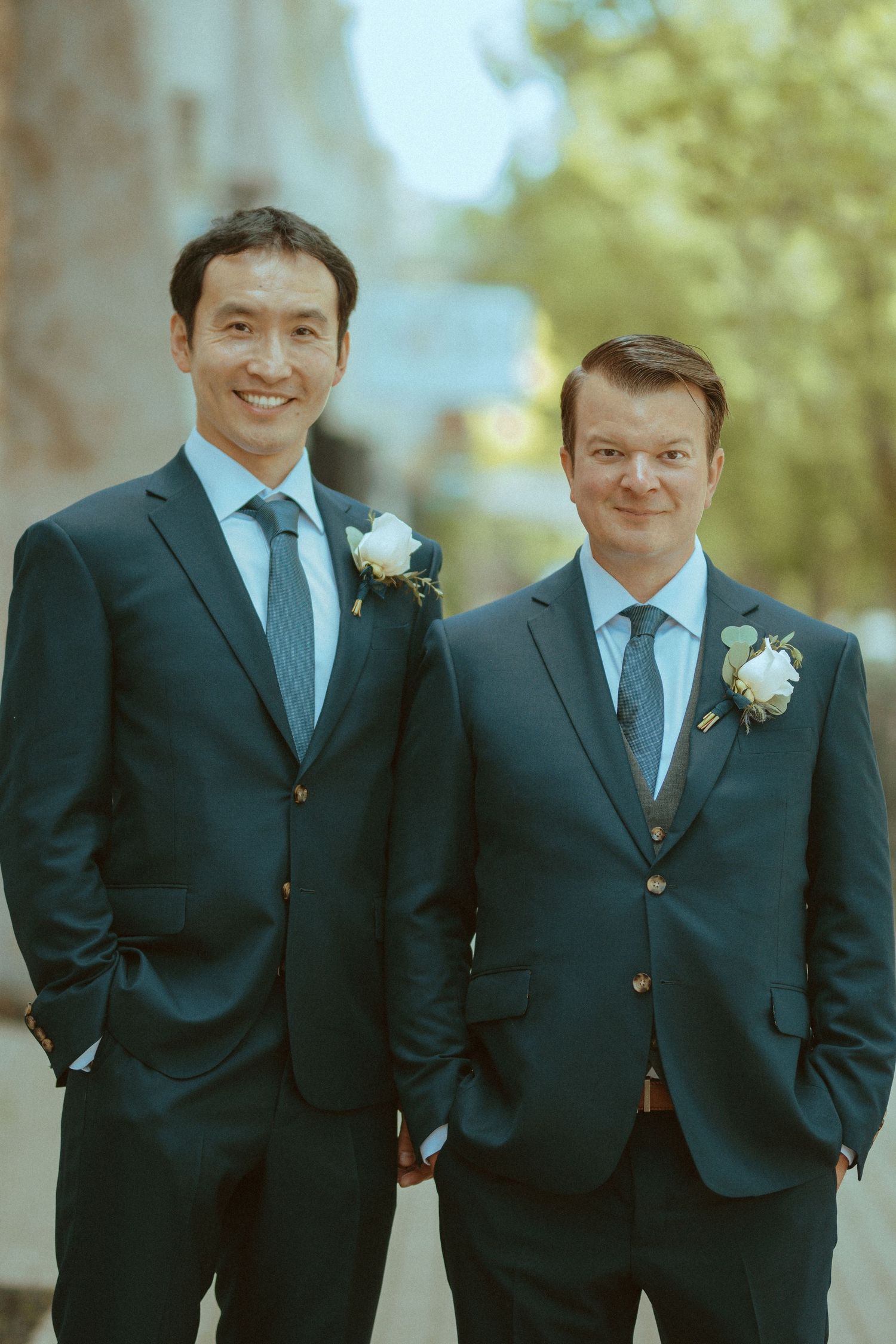 Wedding party members in coordinated navy suits pose casually outdoors.