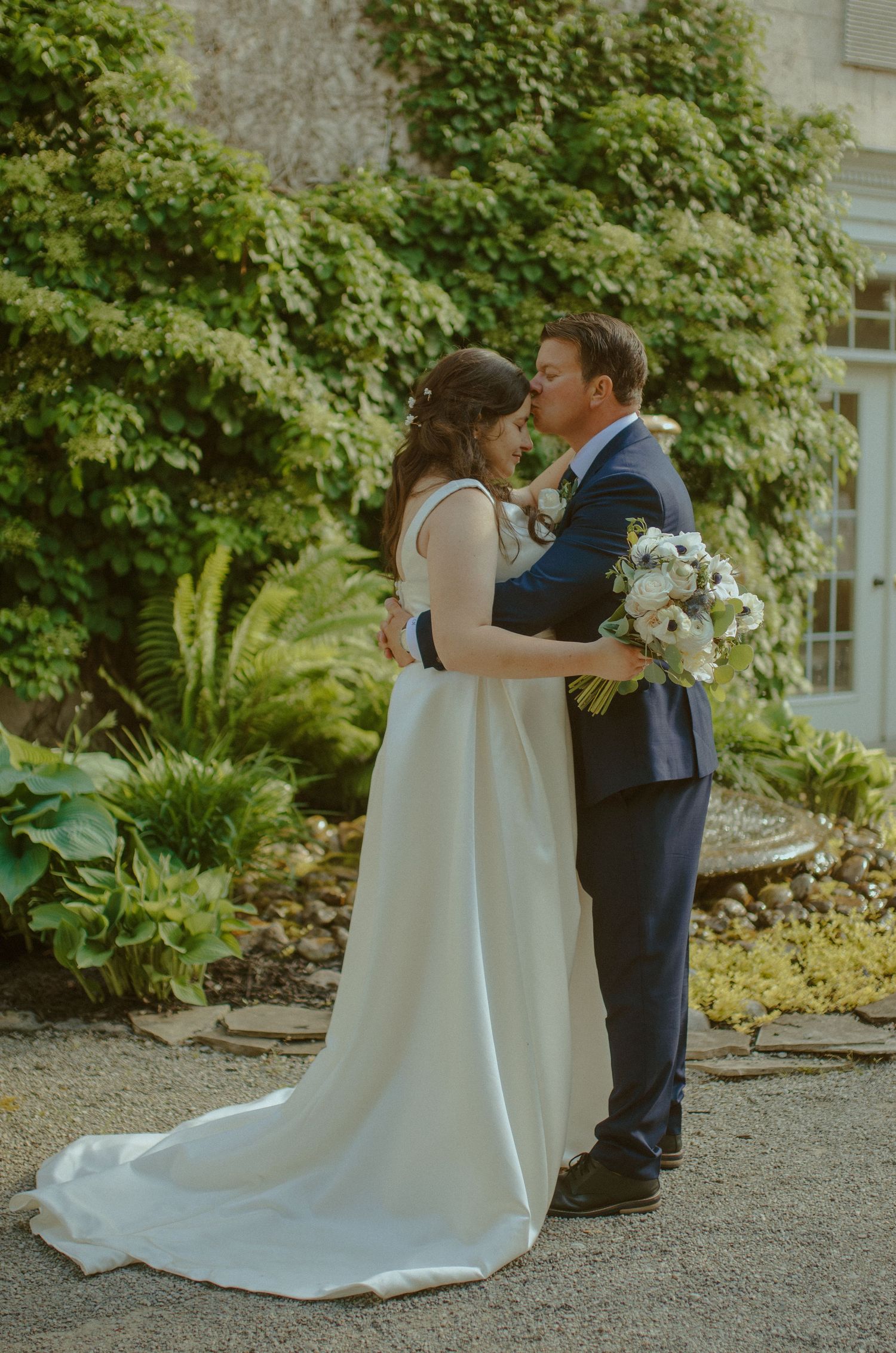 A romantic garden wedding scene with a couple embracing among lush greenery.