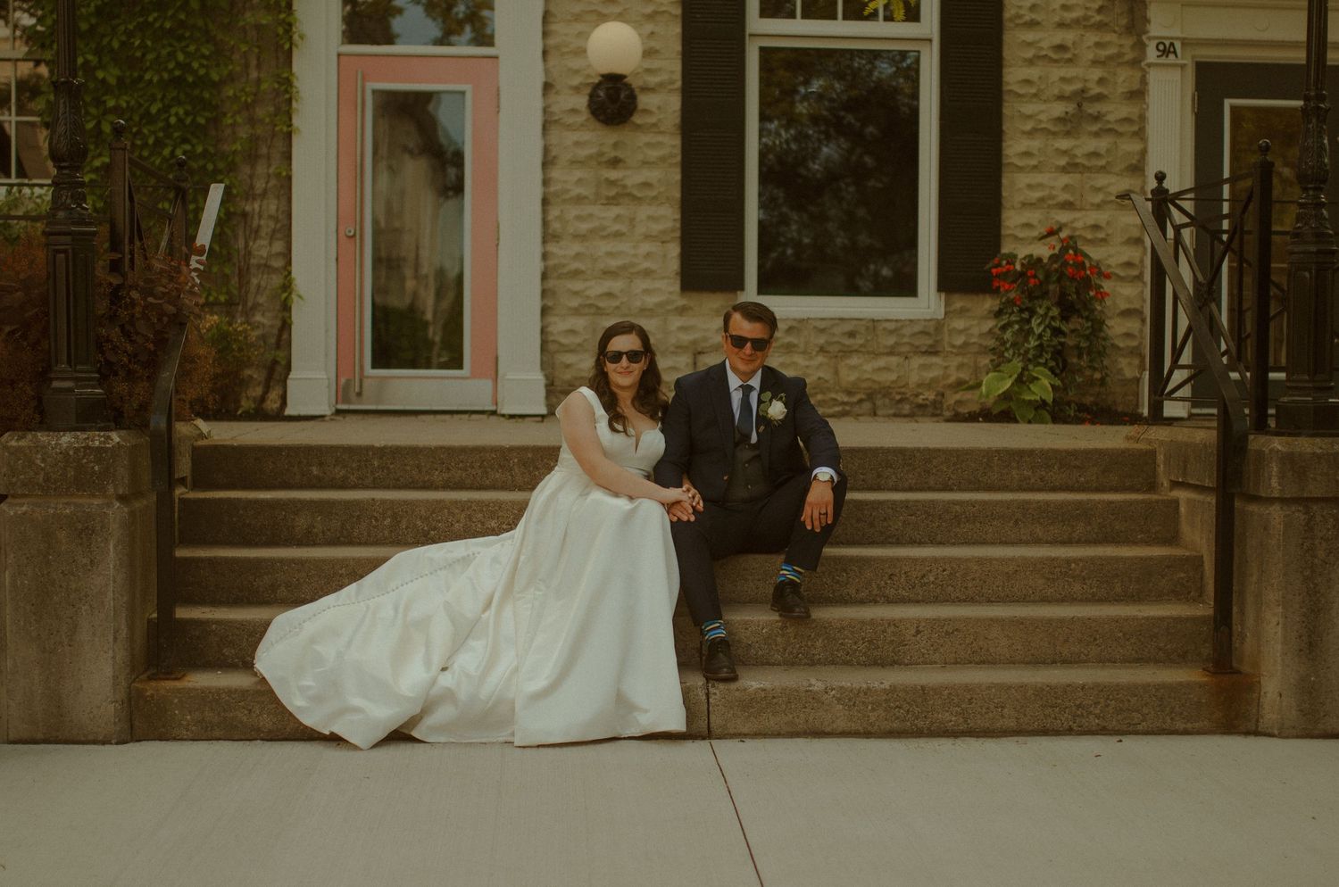 A couple sits together on stone steps during their autumn wedding photoshoot.