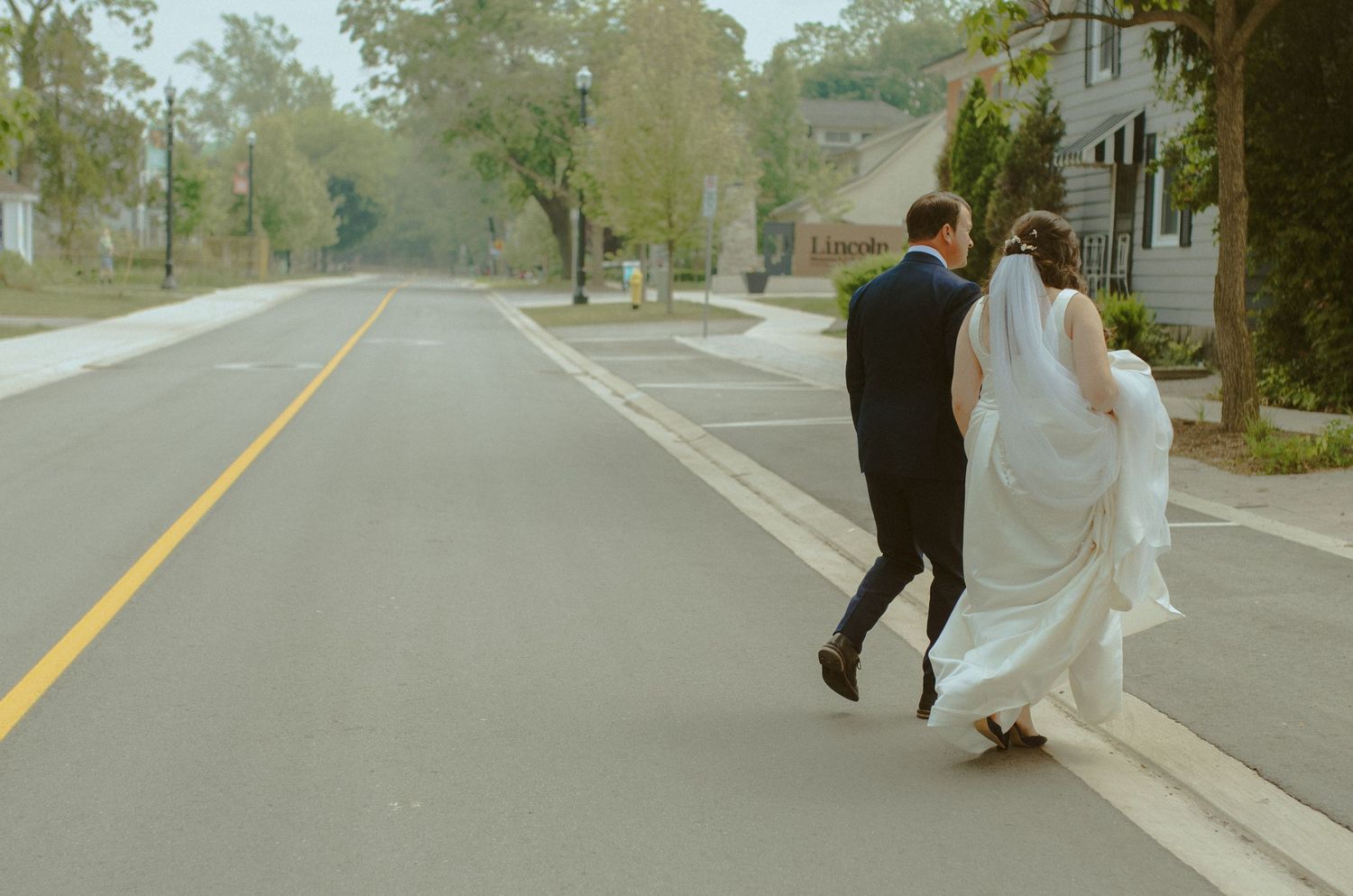 Newlyweds walking down an empty street together after their ceremony.