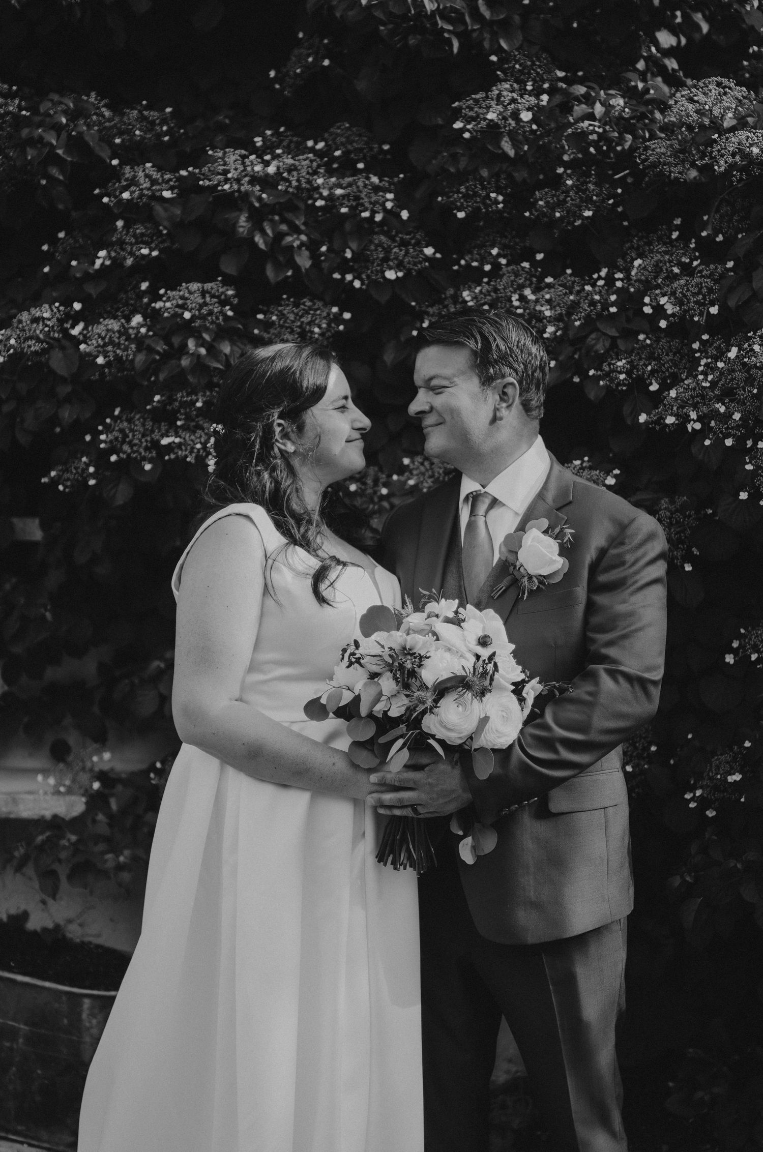 Black and white wedding photo of a couple sharing an intimate moment with florals.
