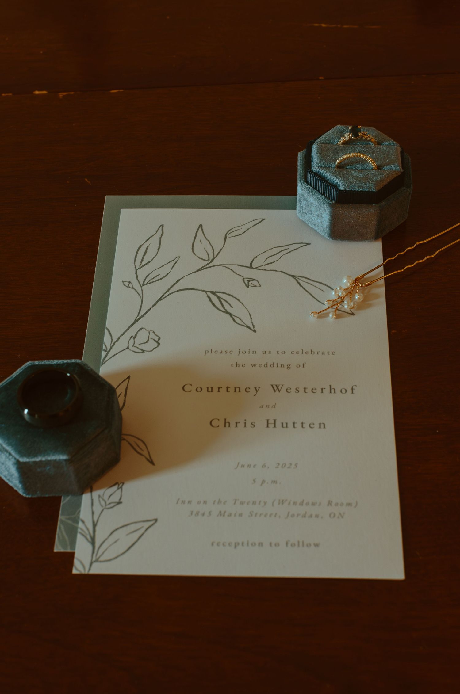 Minimalist wedding invitations with floral line drawings on dark wood background.