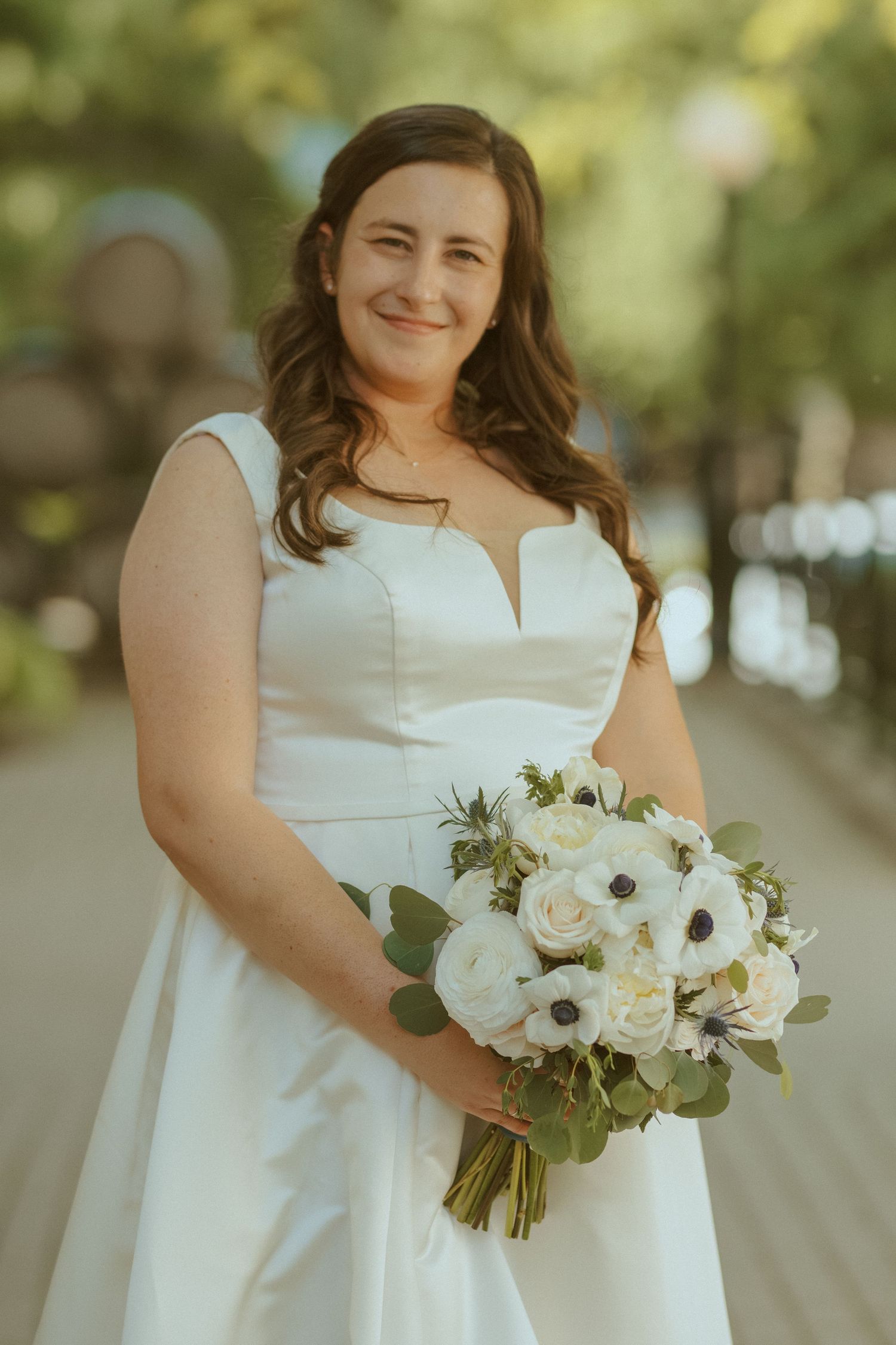 A wedding portrait featuring a white dress and elegant bouquet of white roses and anemones.