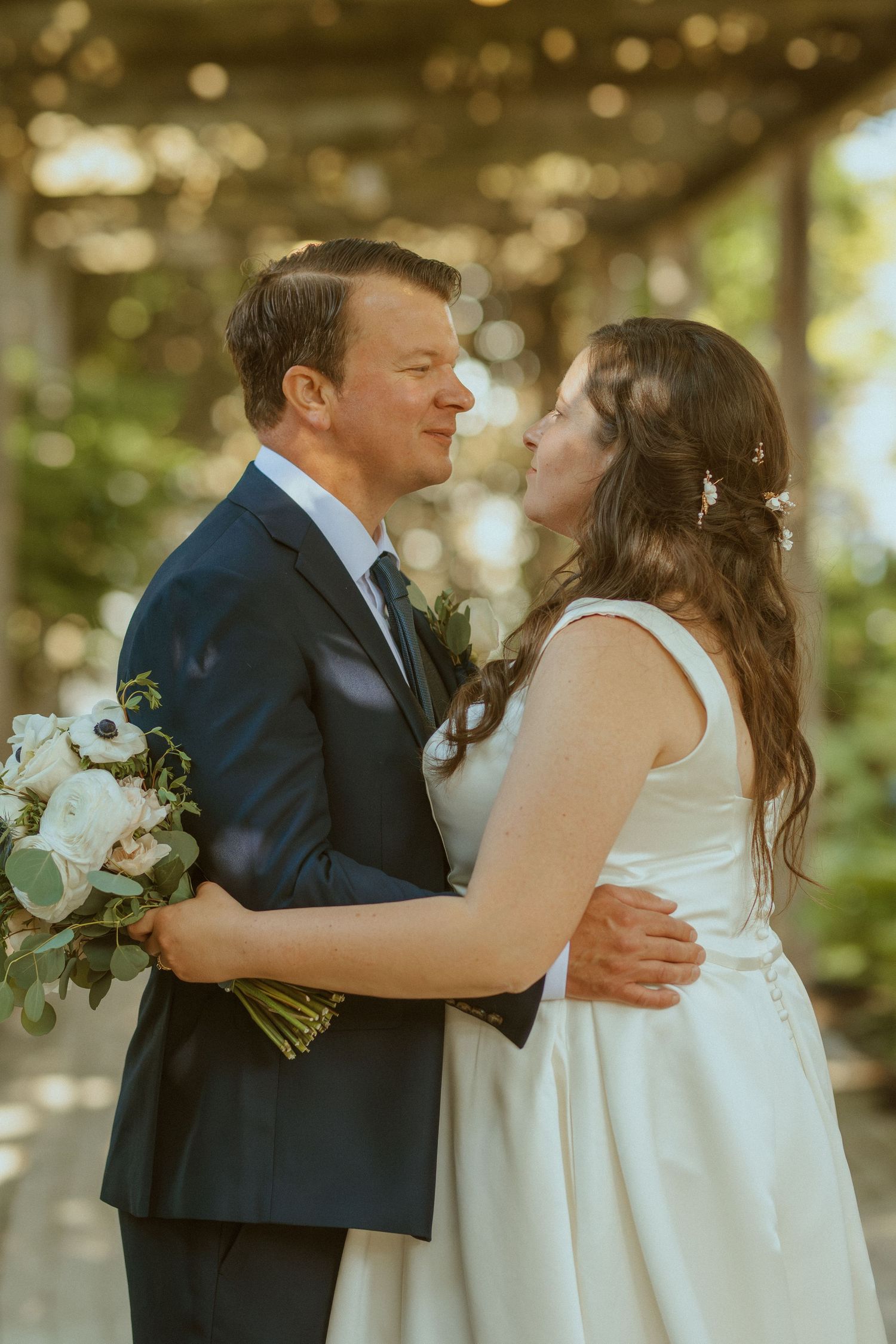 Newlyweds sharing their first kiss during an outdoor wedding ceremony with greenery in the background.