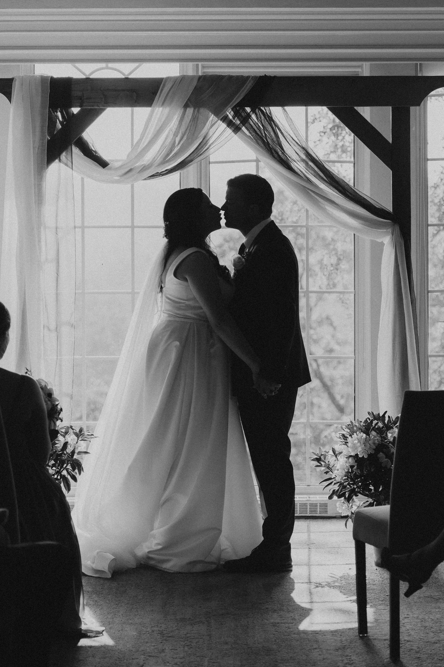 Dramatic black and white silhouettes of a couple dancing in an elegant wedding venue.