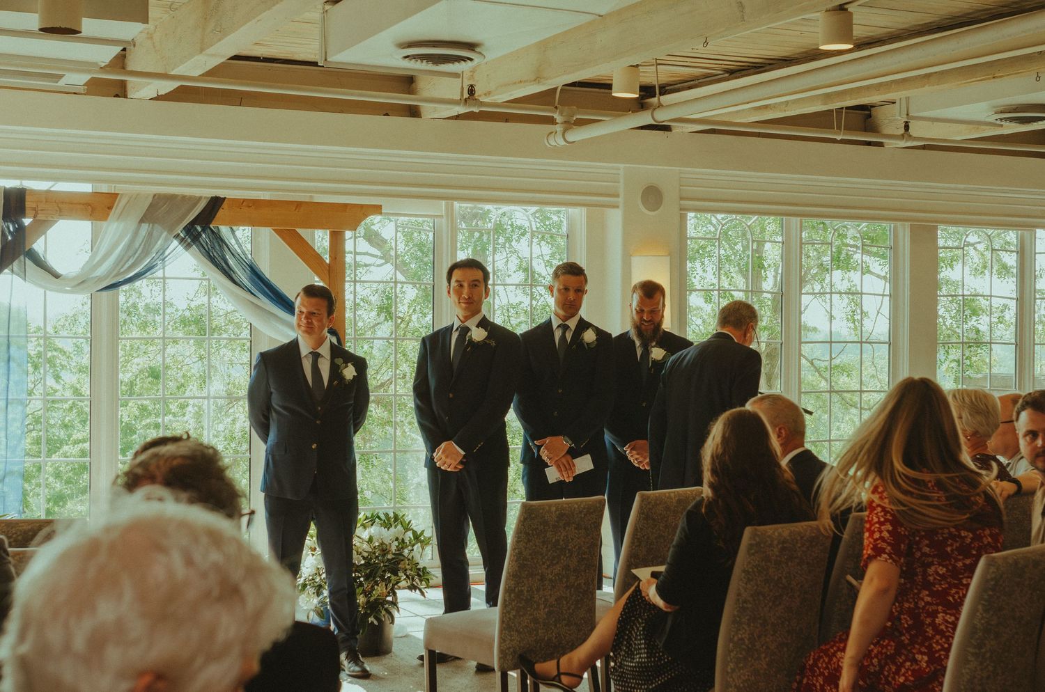 Indoor wedding ceremony venue with exposed beams and large windows letting in natural light.